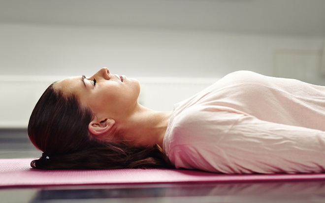 kvinde mediterer på yogamåtte