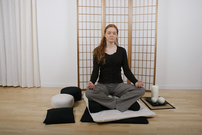 Kvinde mediterer på meditationspude